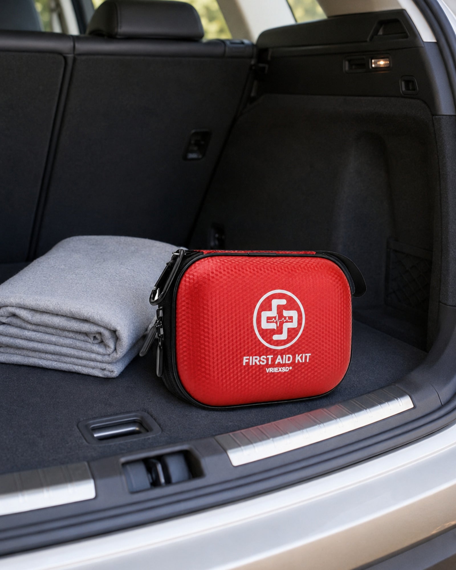 Red VRIEXSD compact travel first aid kit stored in the cargo area of an SUV